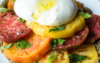 Olive oil drizzled over fresh burrata and heirloom tomatoes