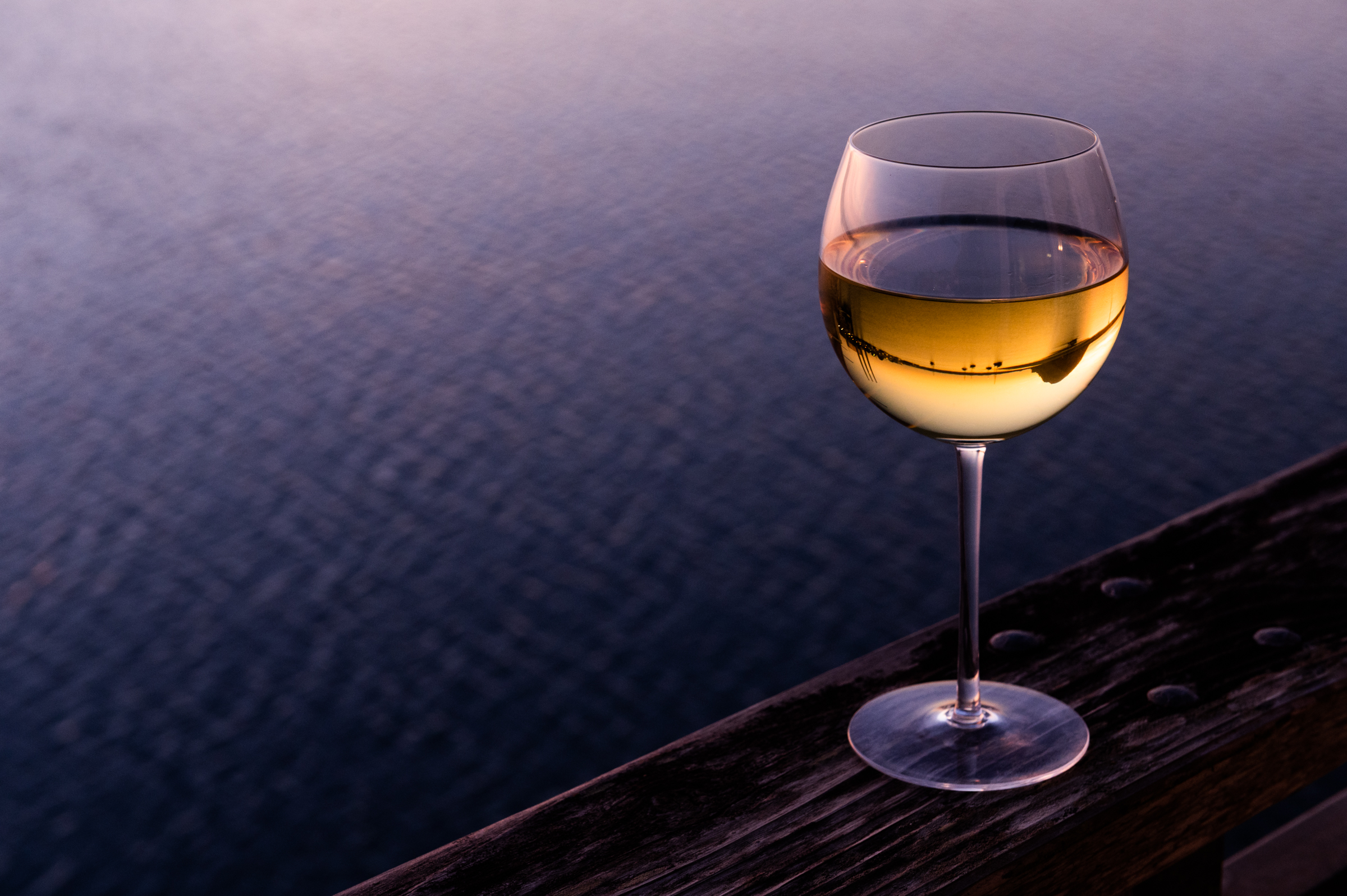 A glass of wine reflects Morro Rock at sunset