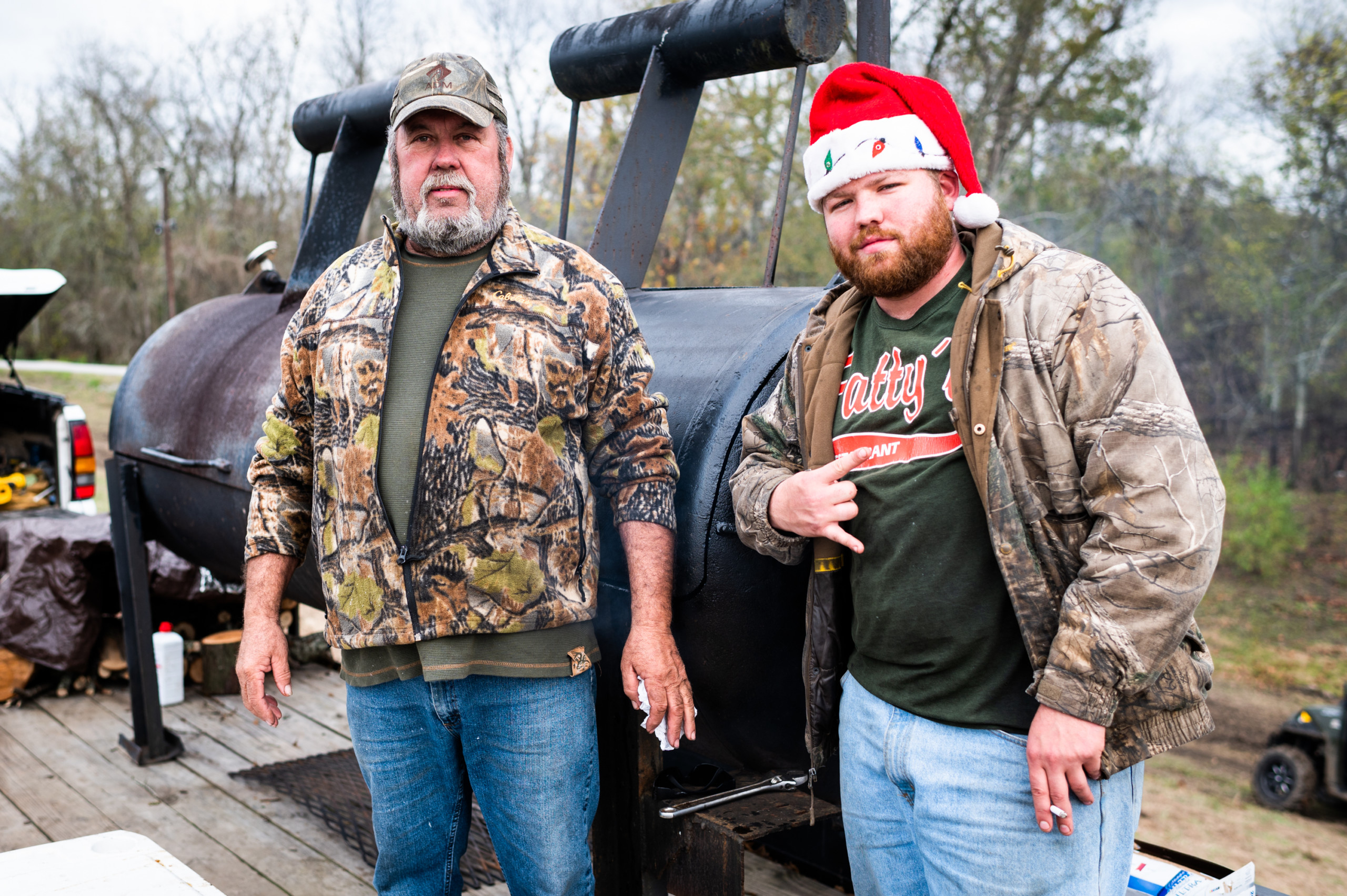 Two of the crew members who built the structure stand in front of smoker filled with two wild hogs