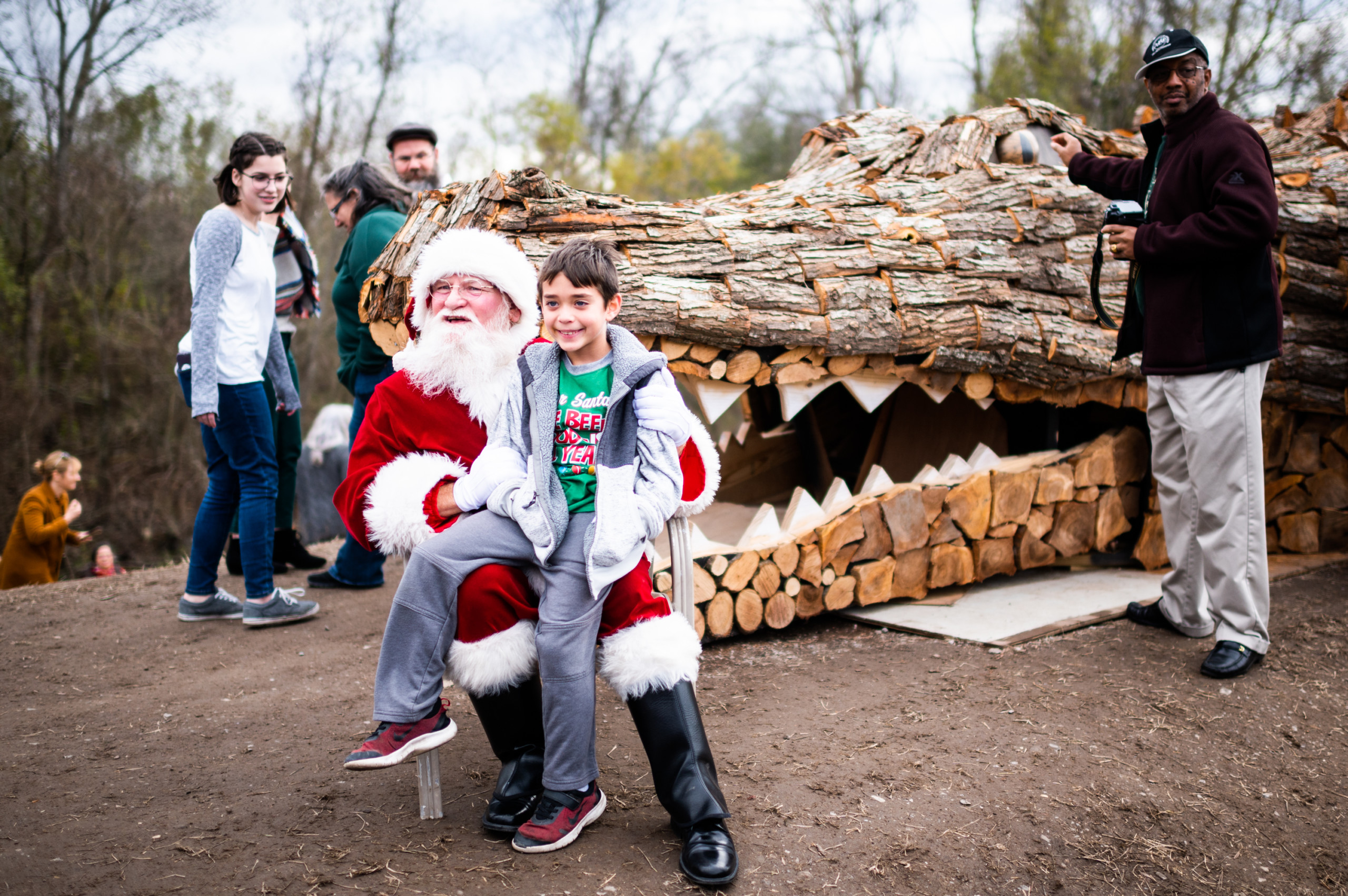 A child poses with Santa in front a 78-foot alligator bonfire sculpture