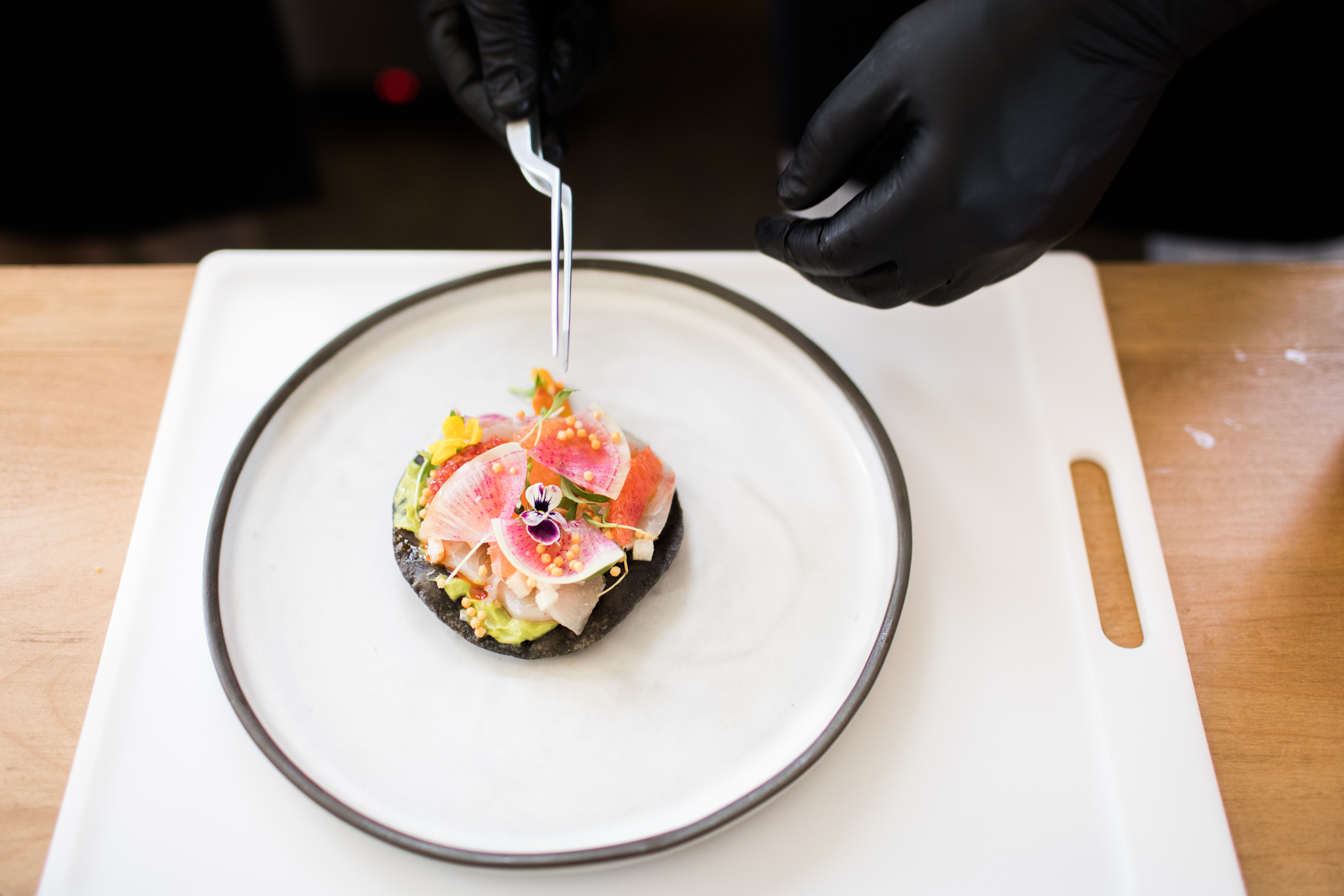 A chef garnishes his dish with edible flowers