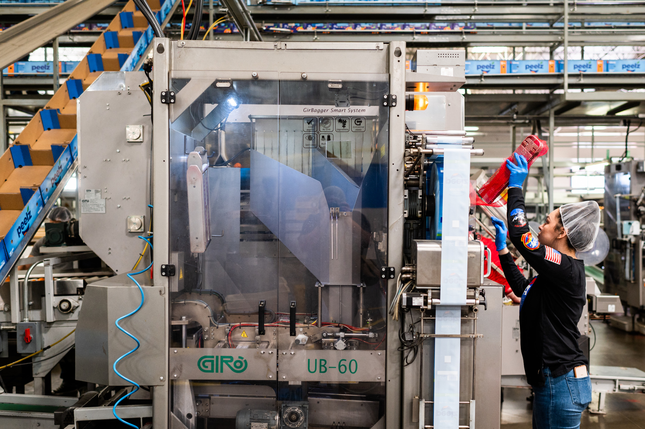 An employee reloads a spool of netting for automated bagging of fresh fruit