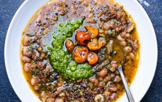 Navy beans stewed with herbs, topped with fresh parsley pistou and pan-roasted cherry tomatoes