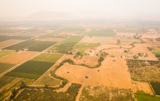 Farms in grids surrounding a river running through the eastern San Joaquin Valley