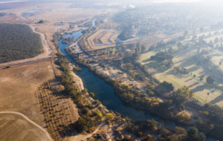 An aerial scene showing the curve of the San Joaquin River cutting between Fresno and Madera