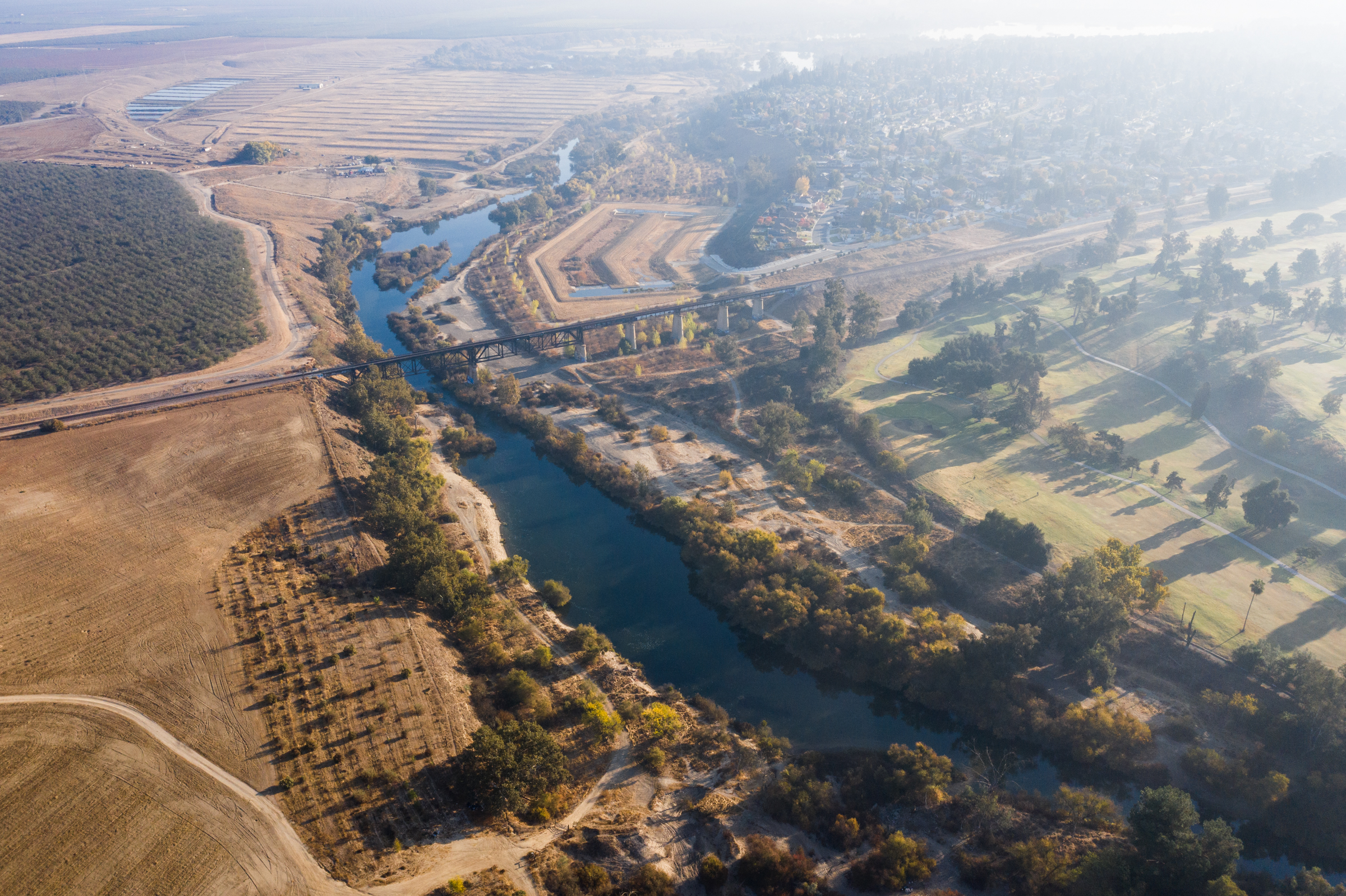 An aerial scene showing the curve of the San Joaquin River cutting between Fresno and Madera