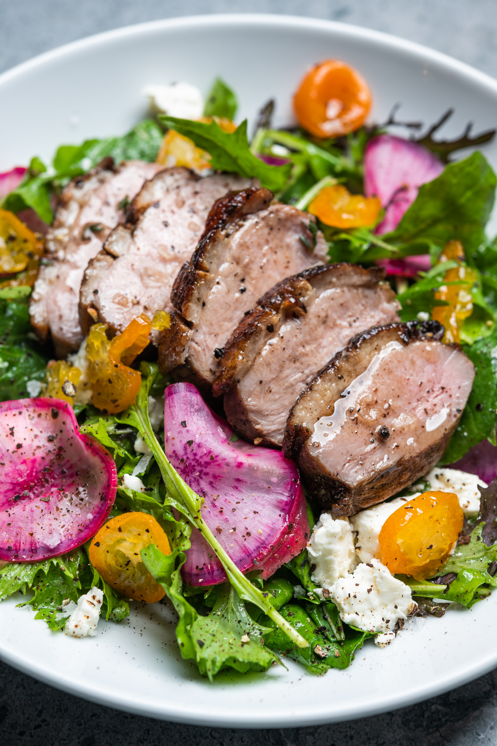 Sliced duck breast and candied kumquats over a salad of arugula, feta, pickled radishes and carrots