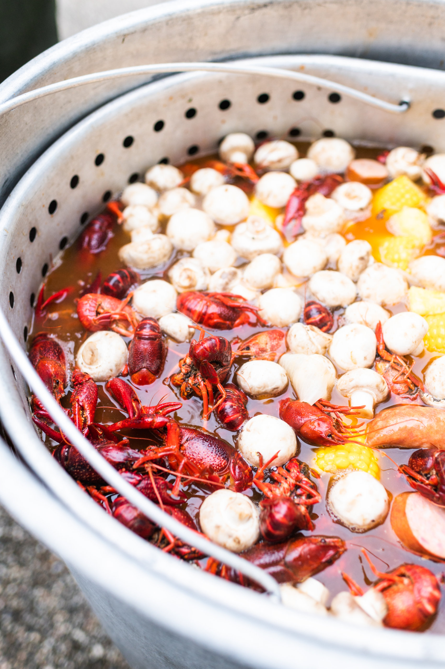 Crawfish soaking after the boil, with mushrooms, corn, sausage, pineapple, and canned green beans