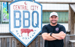 James Cruse poses in front of a Central City BBQ sign