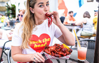 Rémy Robert sucks the head of a crawfish while modeling a t-shirt from Dee Taylor