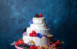 A cake with four tiers of California-made cheese, decorated with produce and California prunes