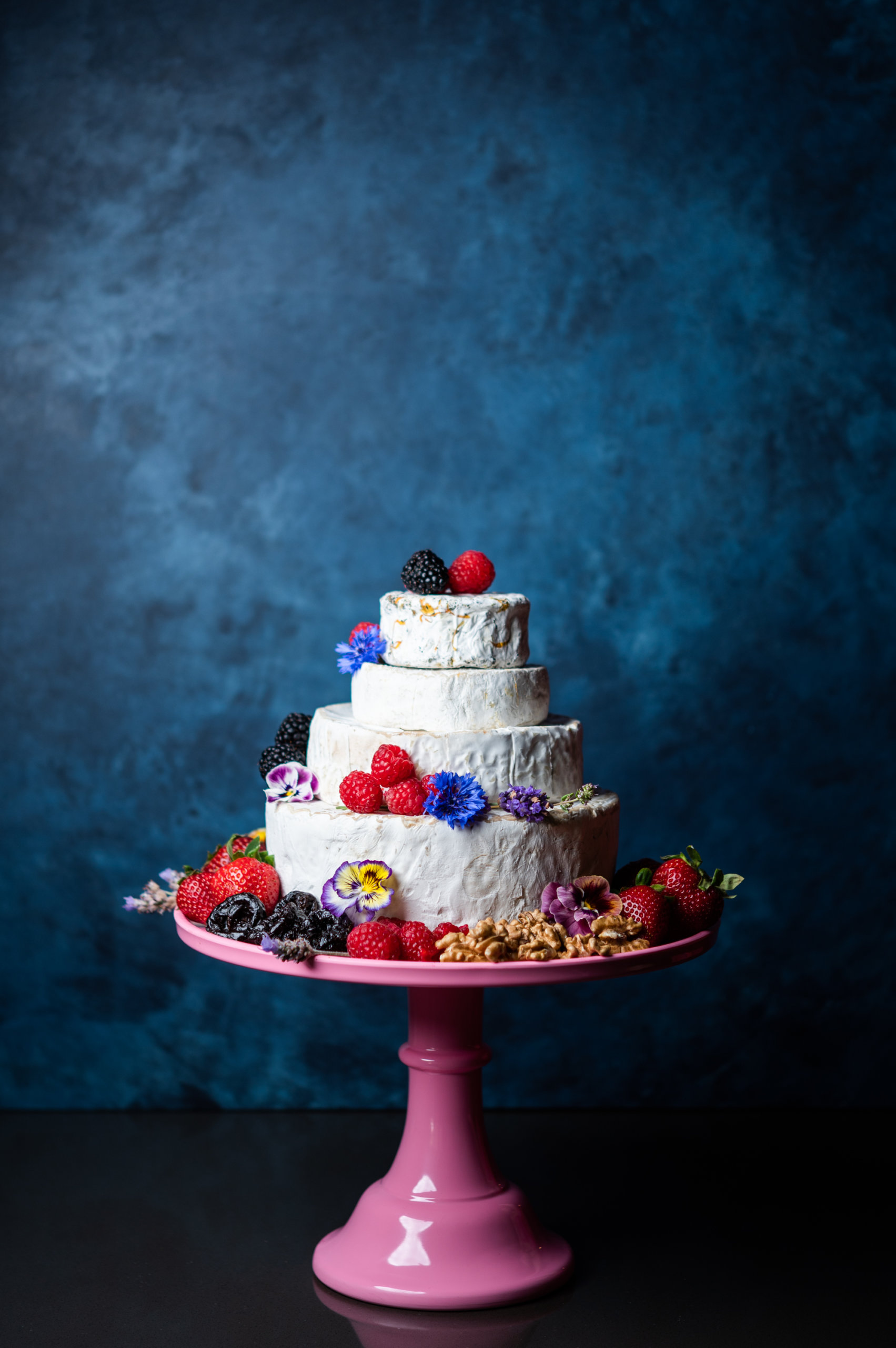 A cake with four tiers of California-made cheese, decorated with produce and California prunes