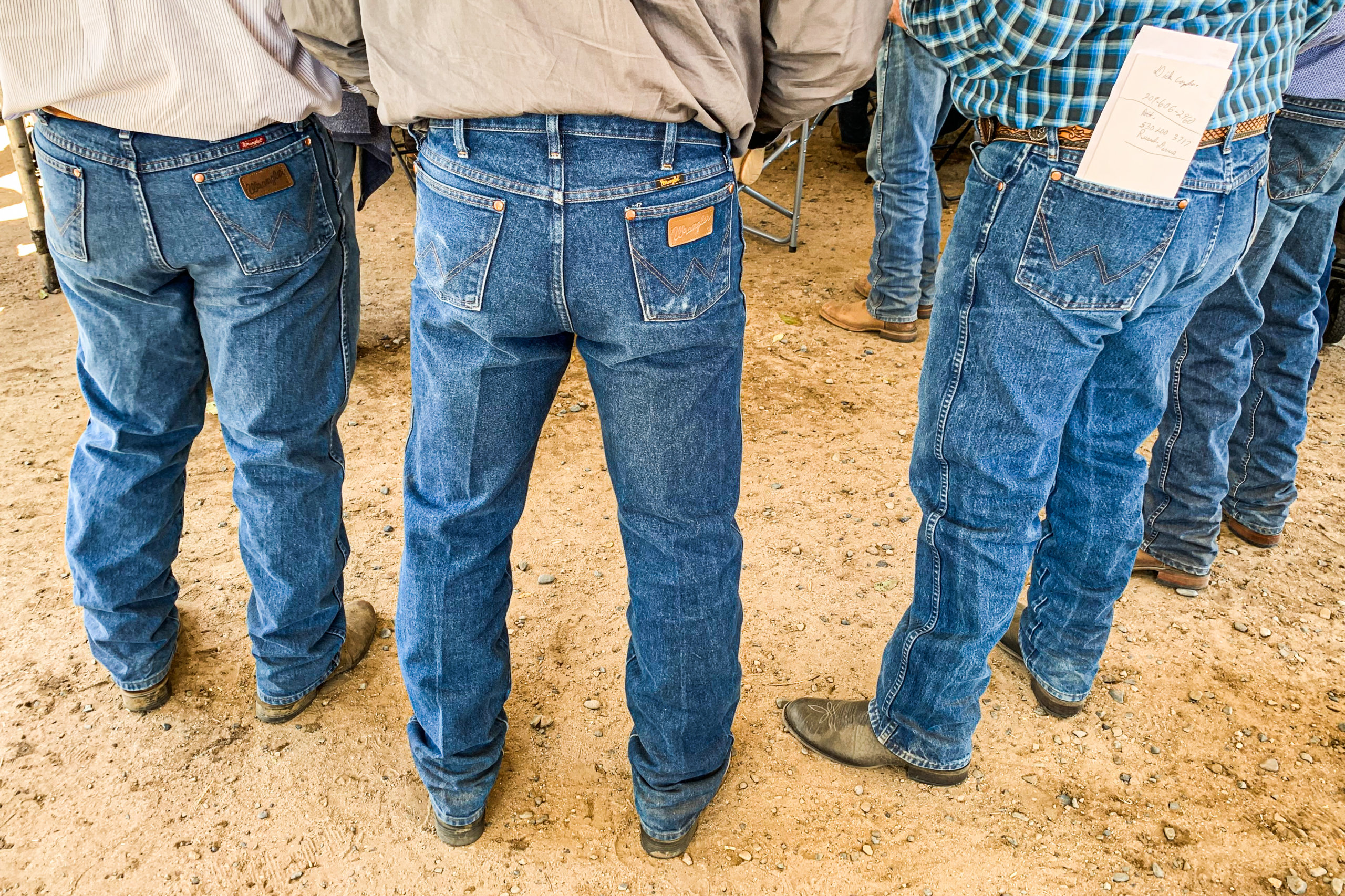 A group of men wearing plaid shirts tucked into Wrangler jeans