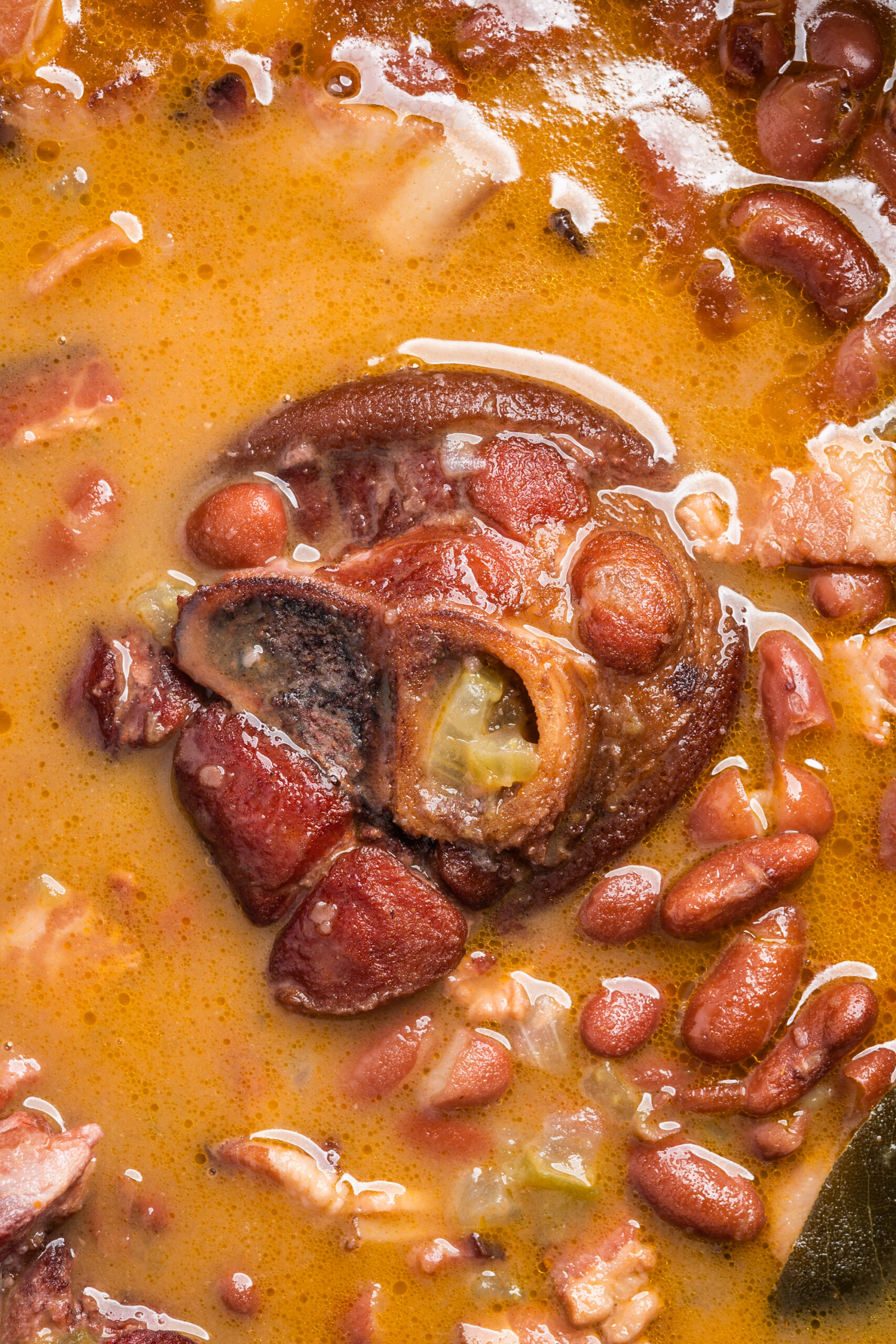 A ham hock floats in a Dutch oven filled with red beans