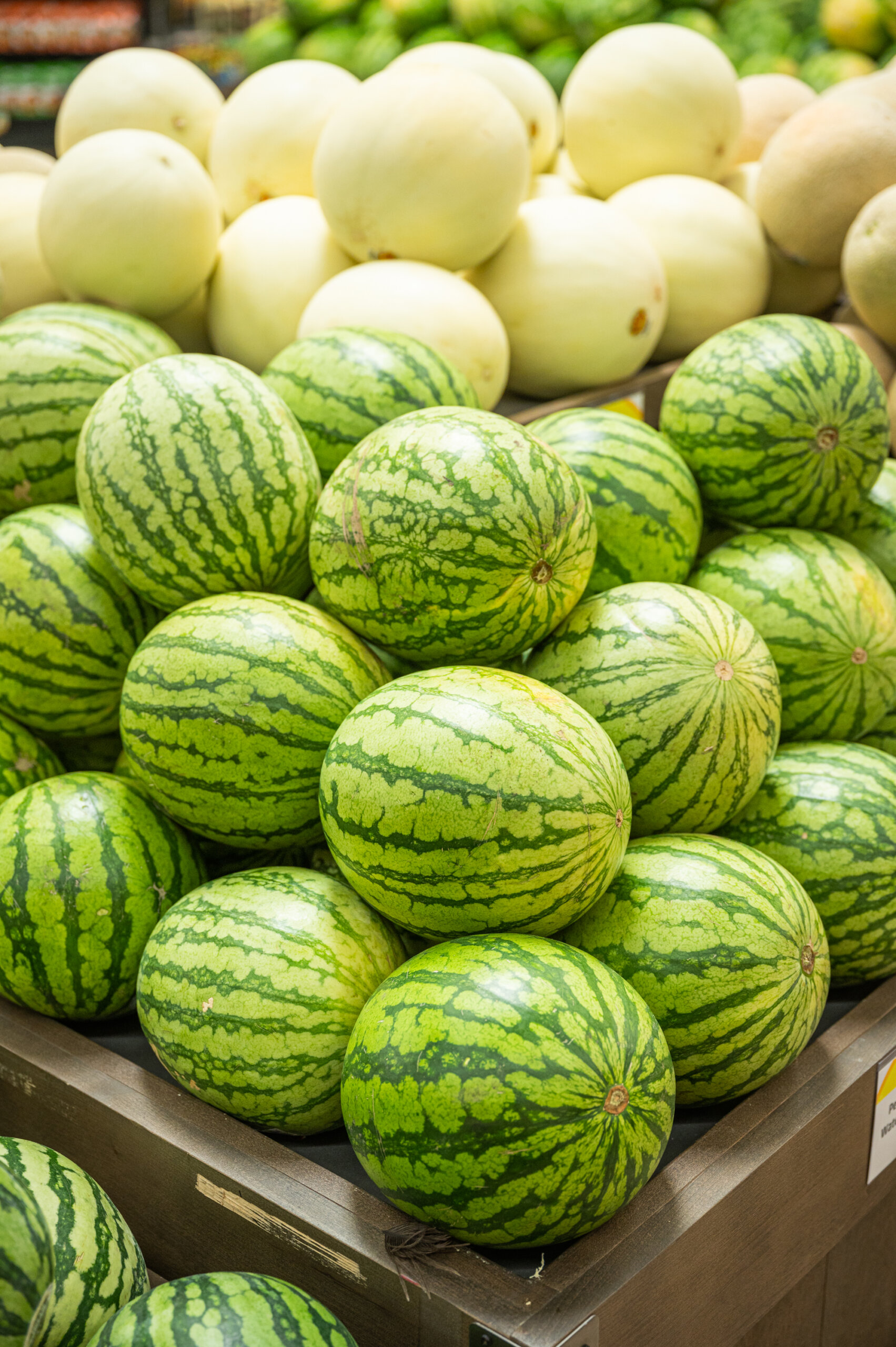 Fresh California watermelons and cantaloupe stacked in a grocery store display