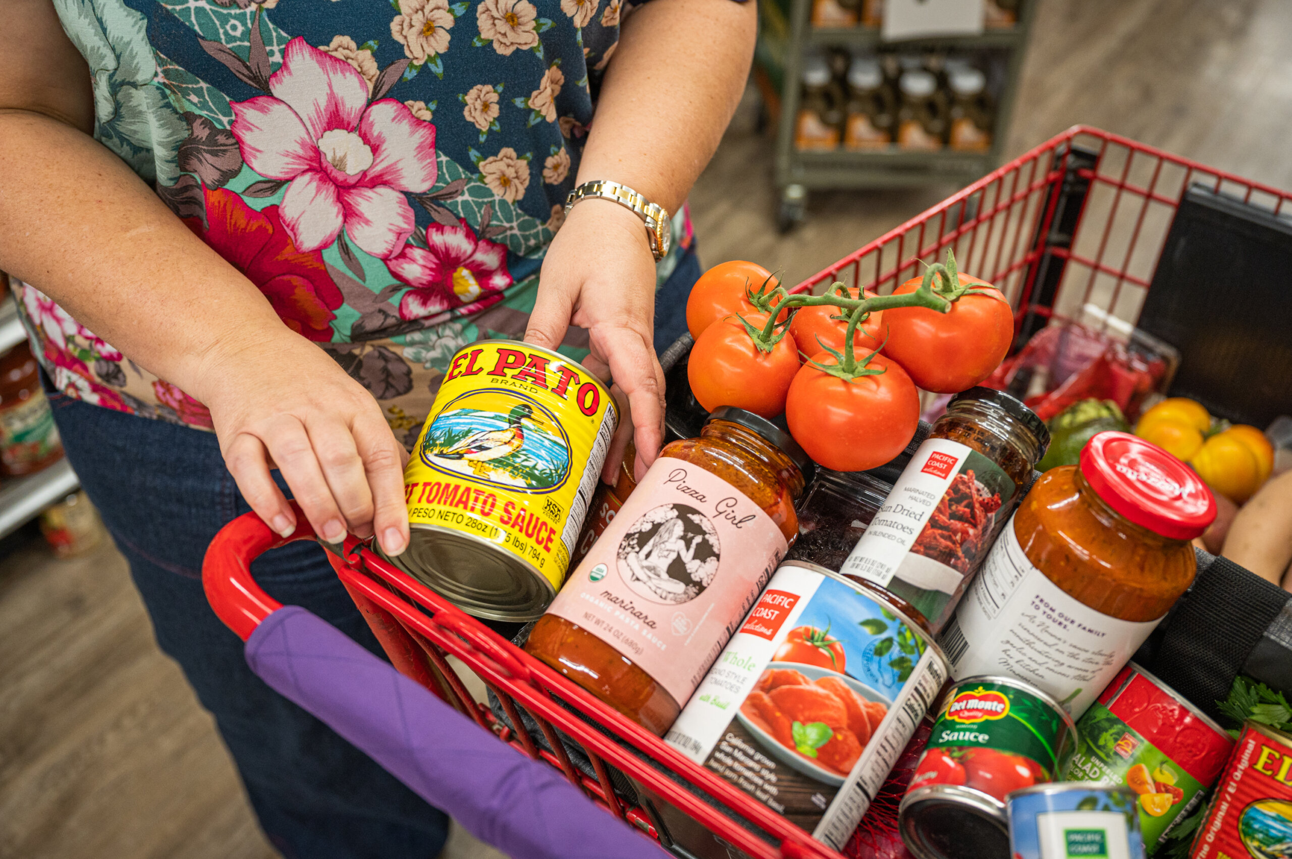 A grocery store shopper adding a can of California-grown tomatoes to her shopping cart