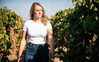 Courtney Gillespie of Life's Grape walks through a vineyard growing dried-on-vine grapes