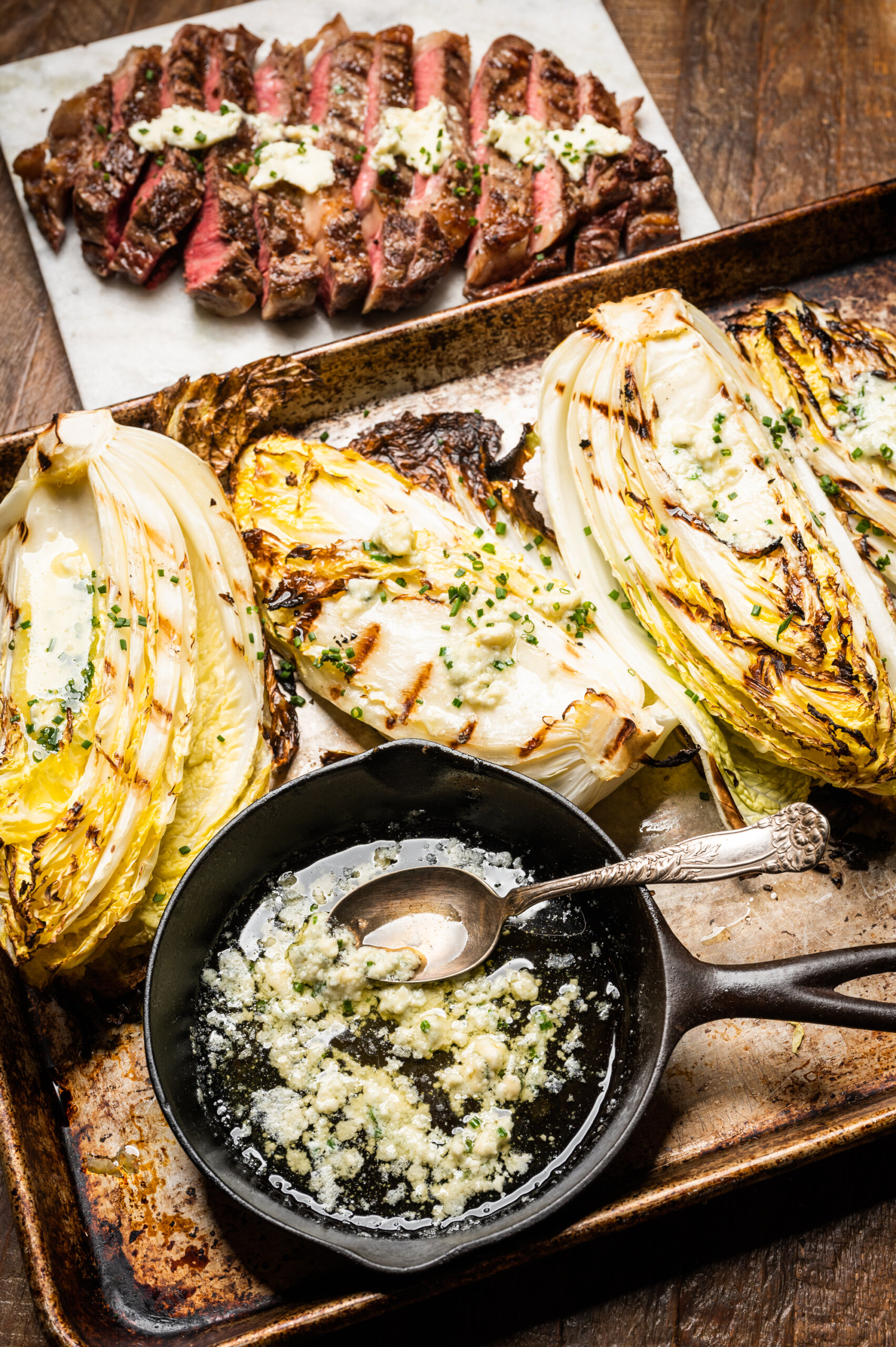 A spread of grilled napa cabbage and steak with bleu cheese butter and chives