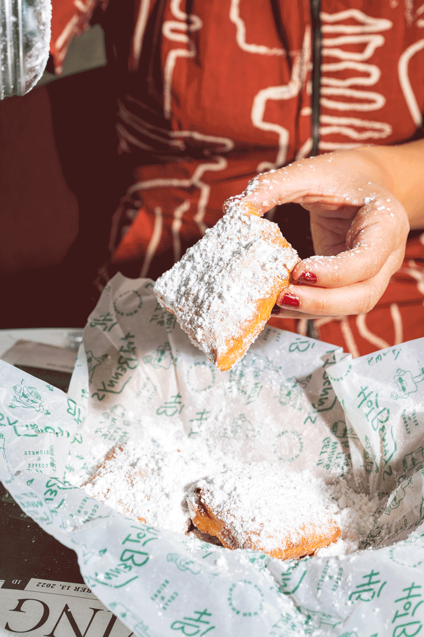 Animation of powdered sugar being poured onto a fresh beignet