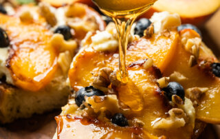 Close-up of honey drizzling over peach and ricotta toast