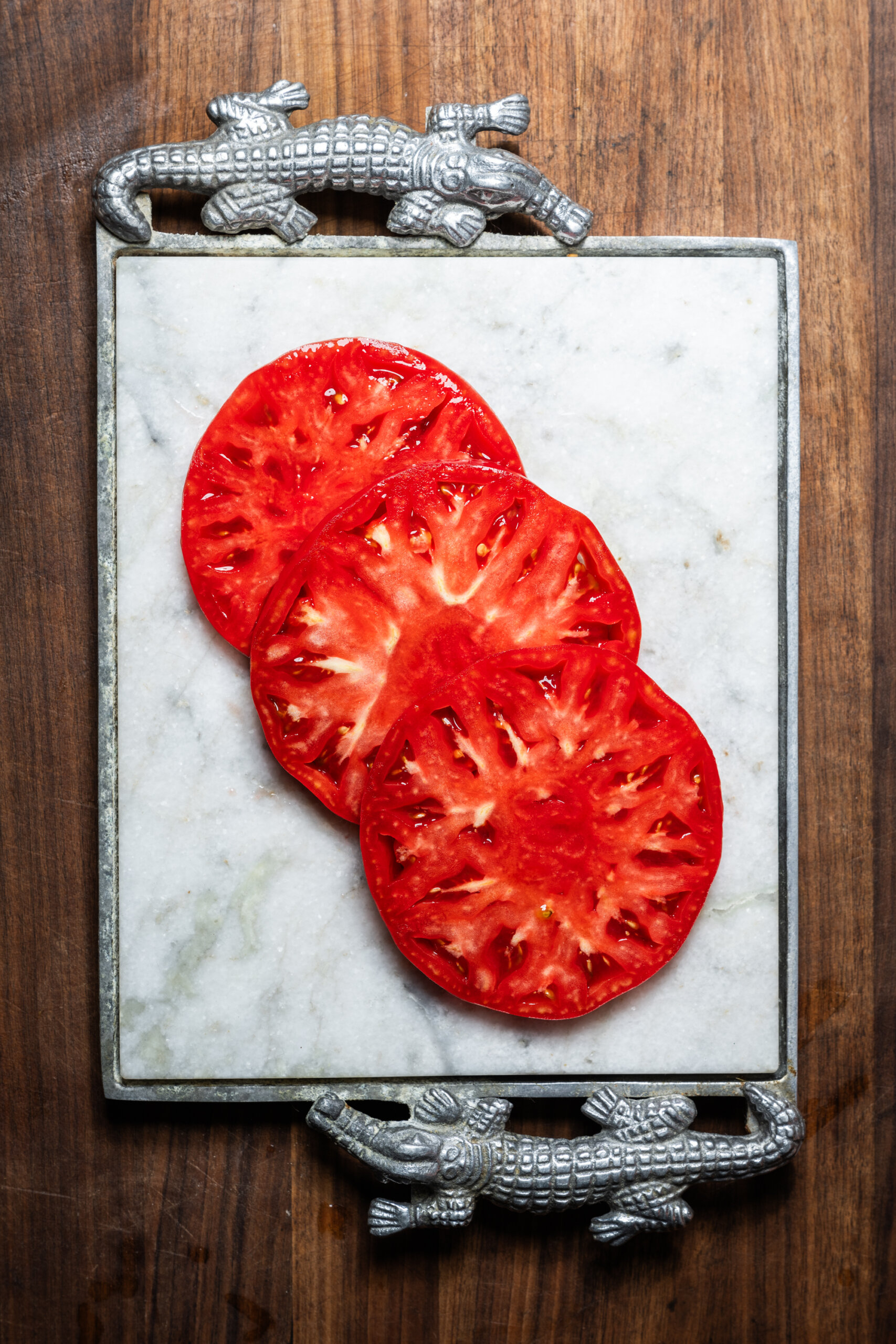Slices of an heirloom brandywine tomato on a marble serving platter