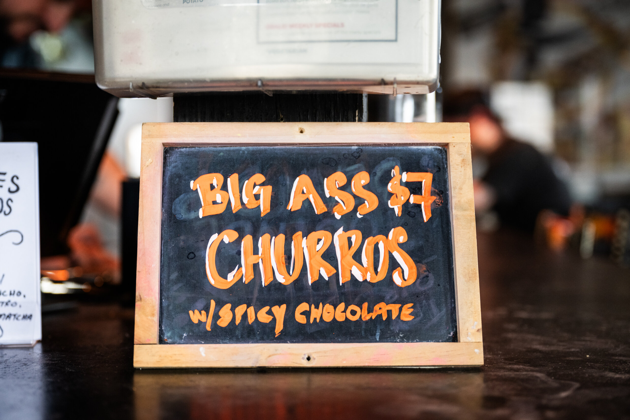 A sign advertising "Big Ass Churros" for $7