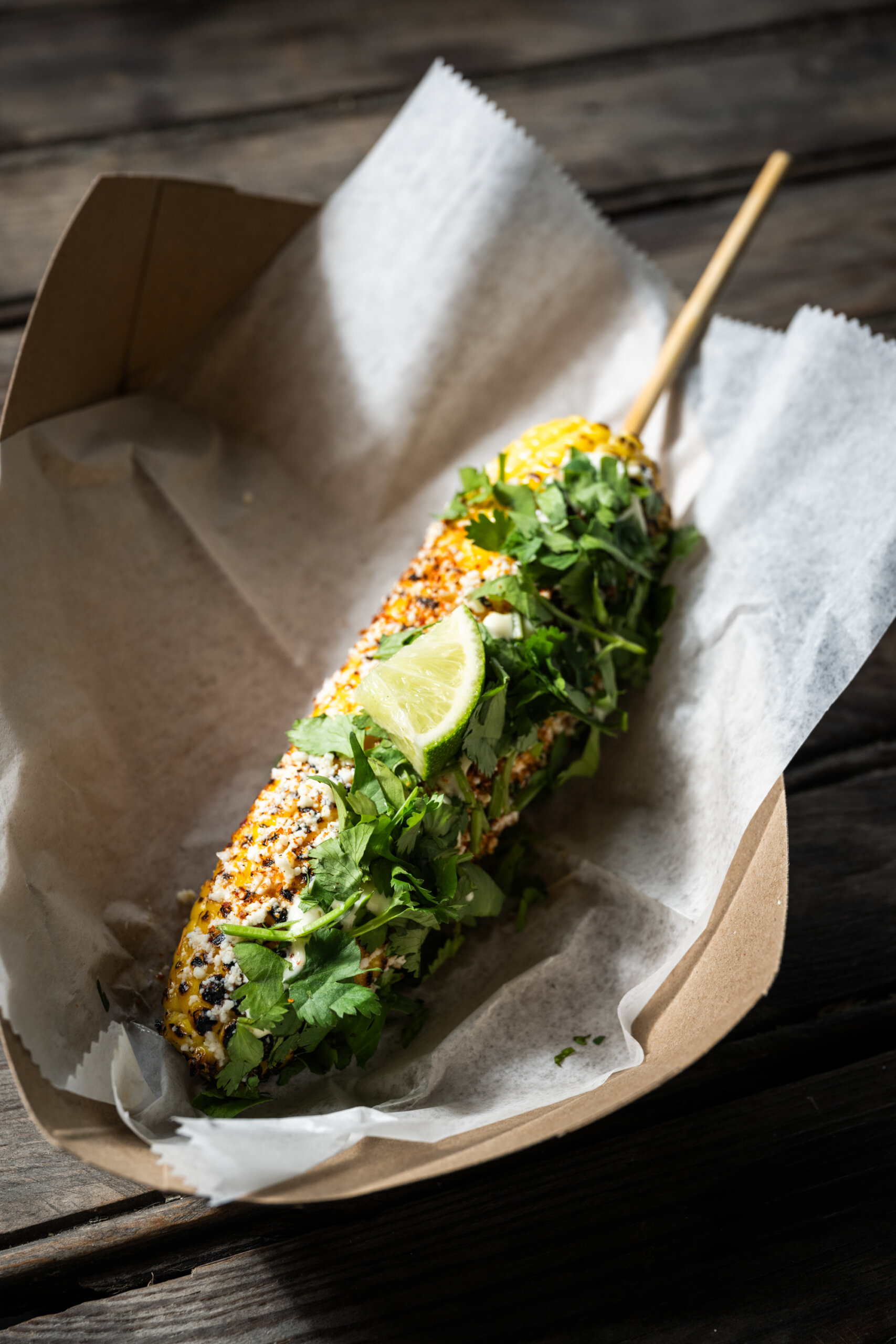 An ear of elote corn with lime and cilantro