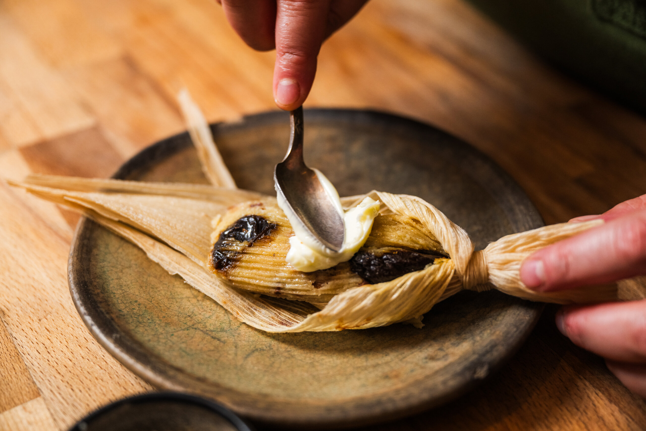 Chef Ana Castro spreads butter over a hot tamal
