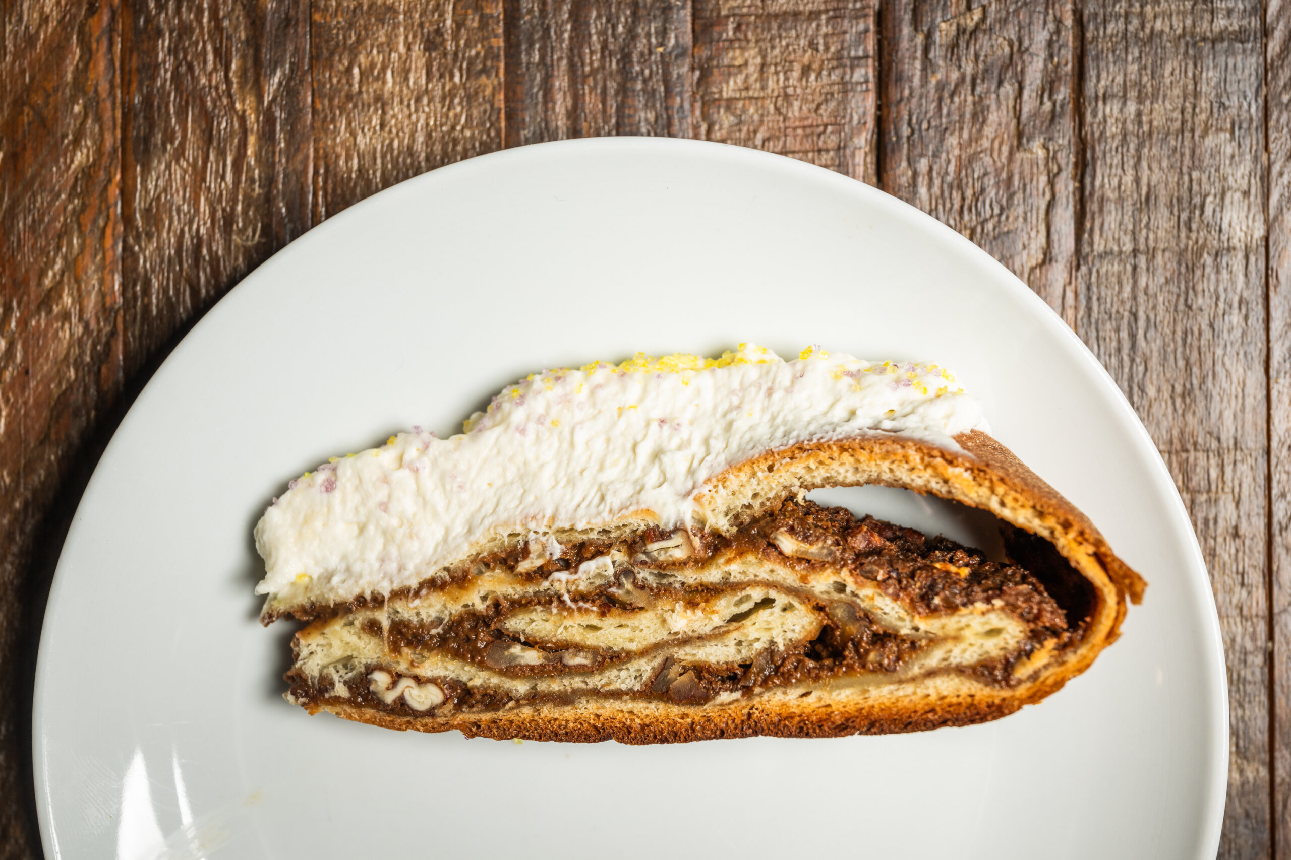 Layers of dough and prune and cream cheese filling in a slice of king cake