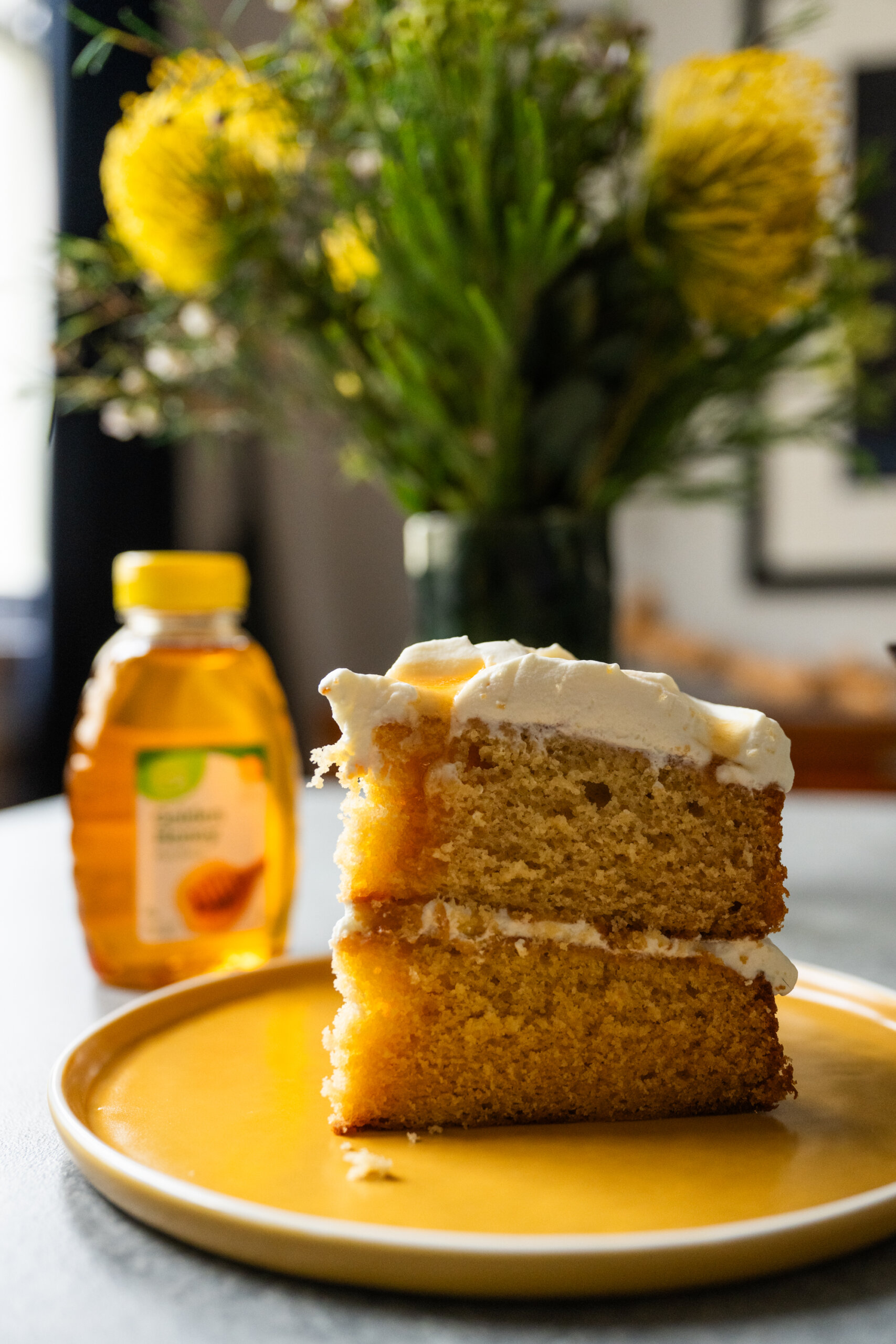 A slice of milk and honey cake next to a bottle of pure honey