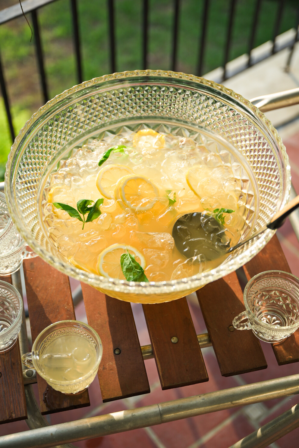 A crystal punch bowl on a Southern porch, filled with lemonade, mint, and bourbon.