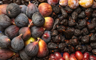 Overhead view of fresh and dried fruit pairings: Prunes, figs, and raisins/grapes.