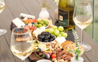 Tablescape at the beach featuring a dried fruit and cheese board and San Joaquin Wine Company's chardonnay.