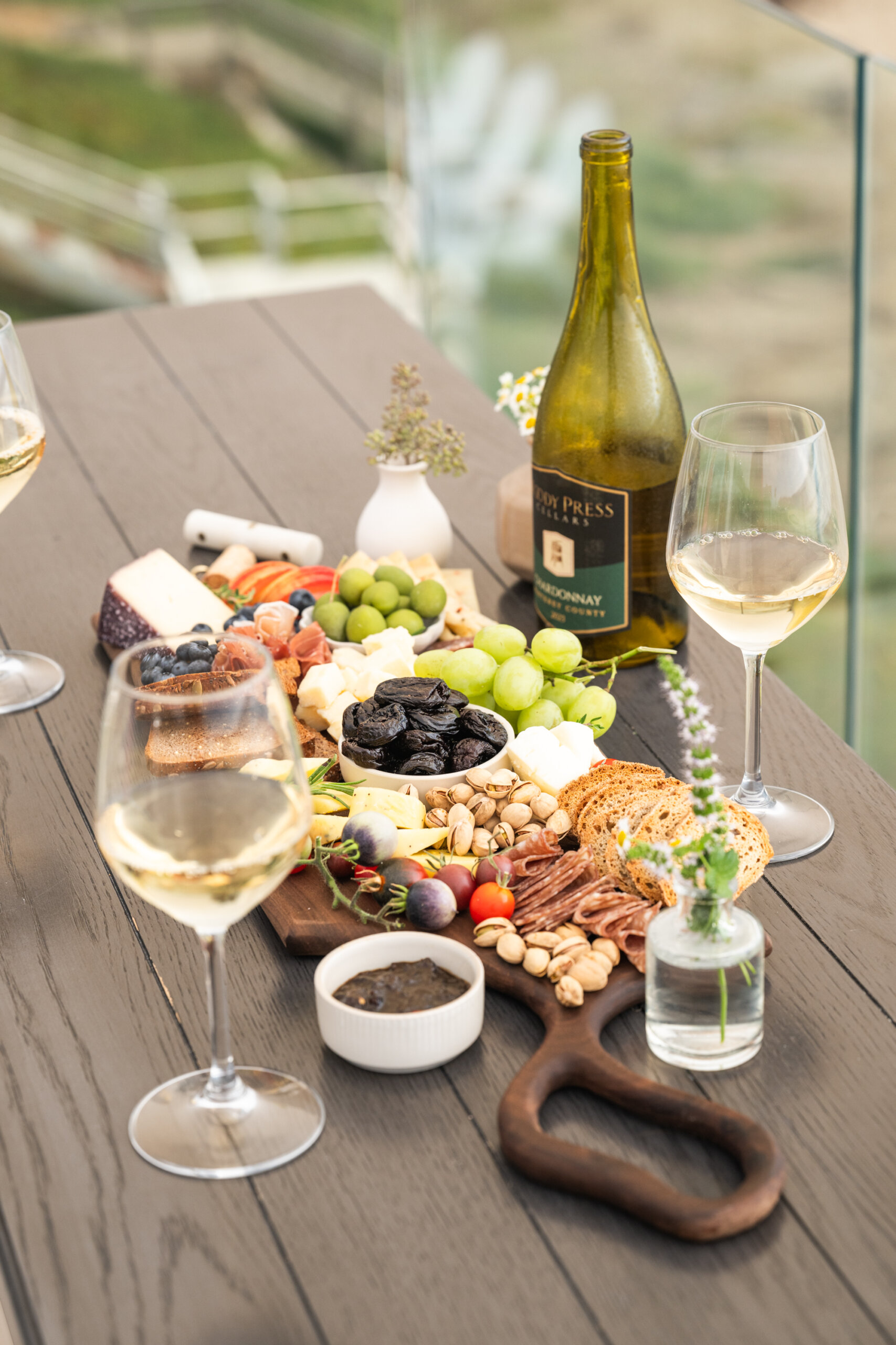 Tablescape at the beach featuring a dried fruit and cheese board and San Joaquin Wine Company's chardonnay.