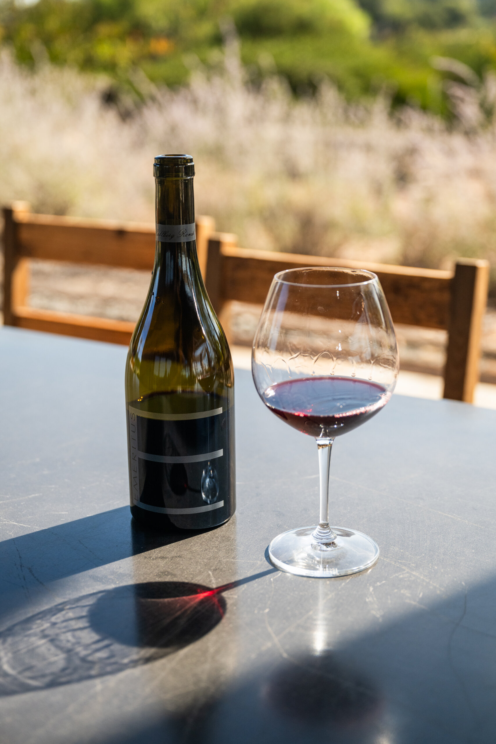 A glass of red wine poured from a bottle of Emeritus Hallberg Ranch