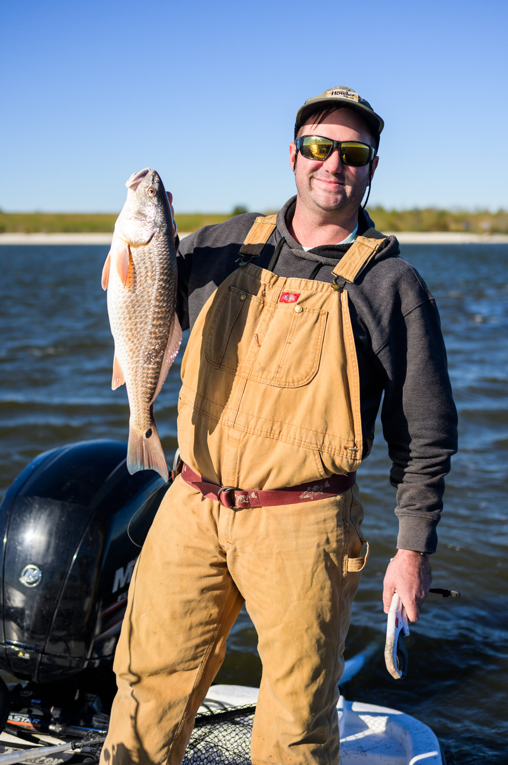 Captain Logan Boudreaux holds up a redfish caught in Bayou Bienvenue