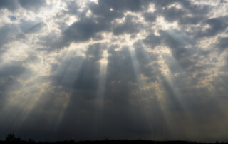 Late afternoon sunlight pokes through dense, spotty clouds over Bayou Bienvenue