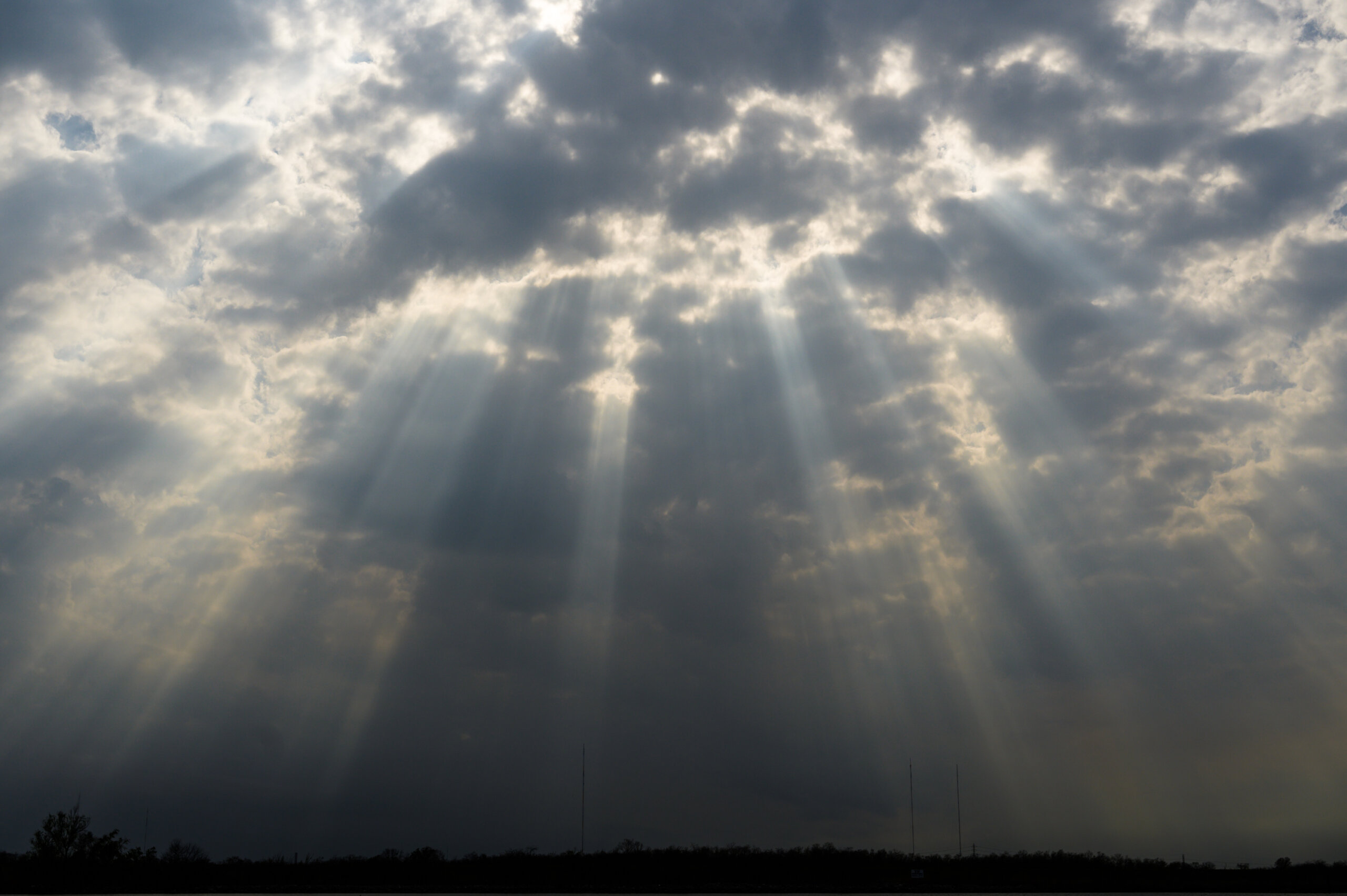 Late afternoon sunlight pokes through dense, spotty clouds over Bayou Bienvenue