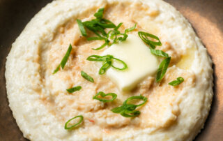 Pureed shrimp paste melting into creamy stone-ground grits, topped with butter and scallions