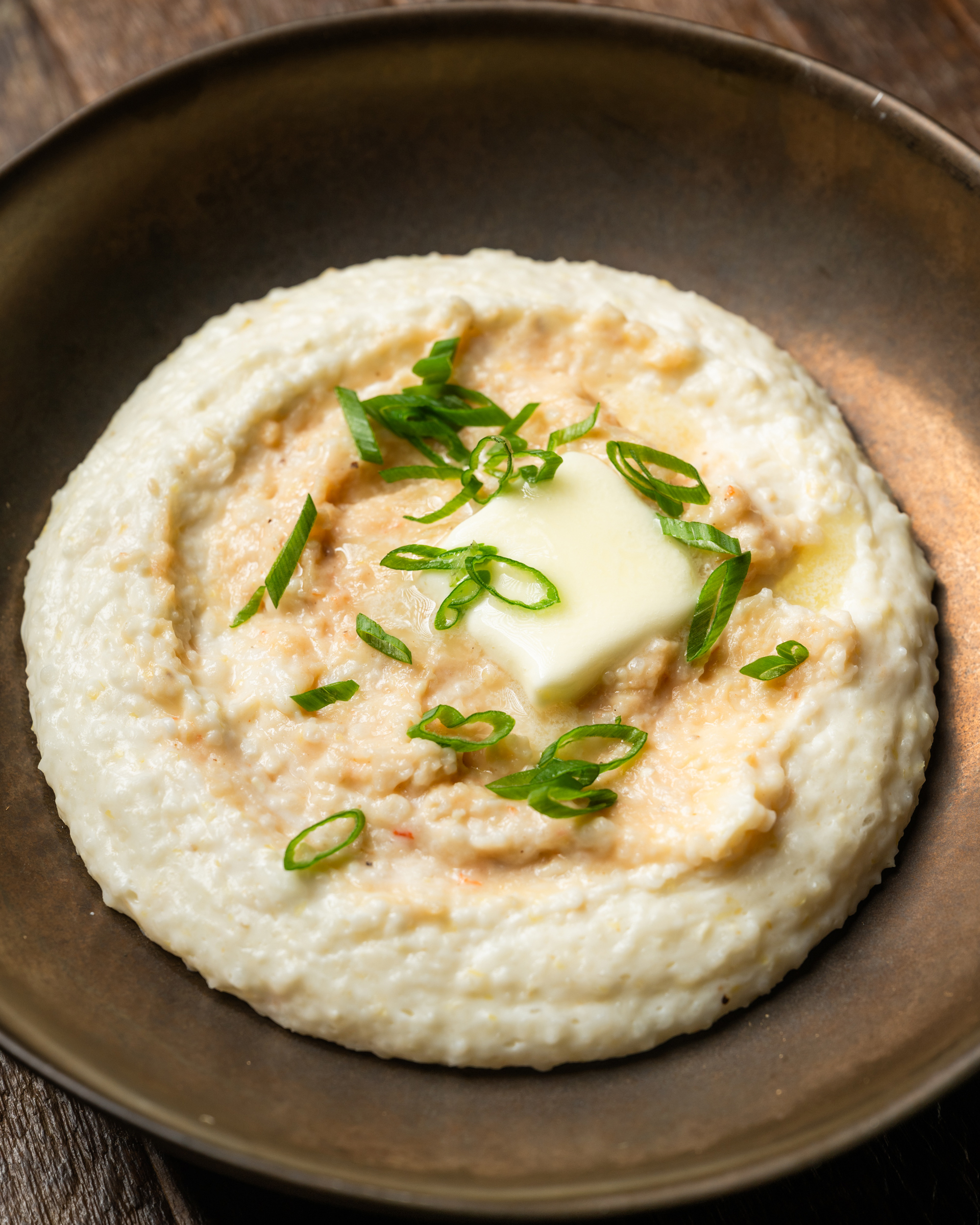 Pureed shrimp paste melting into creamy stone-ground grits, topped with butter and scallions